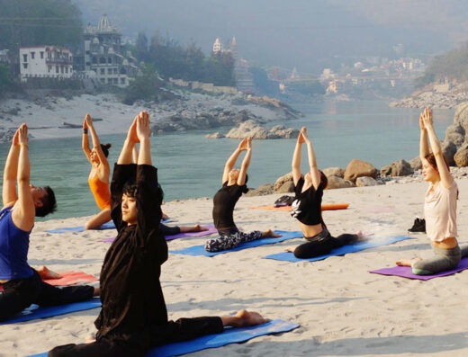 A group of people are shown doing yoga on a beach