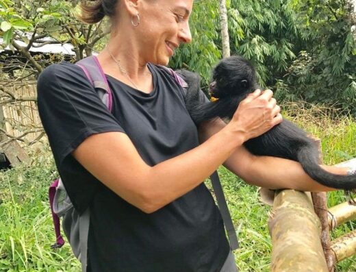 Lynne Nardizzi is shown in the jungle with a monkey perched on her shoulder