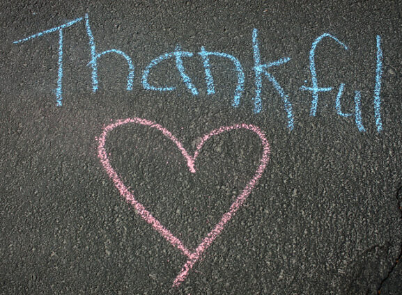 The word "thankful" and a heart in children's writing on the pavement