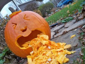 A pumpkin with squinted eyes appears to be puking up its seeds