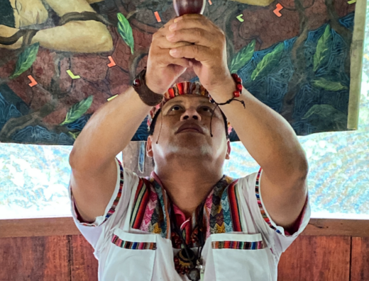 A shaman holds a cup of ayahuasca toward the sky at an ayahuasca retreat