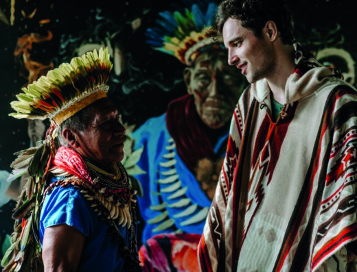 A shaman greets a guest that's wearing a poncho at an Ayahuasca ceremony